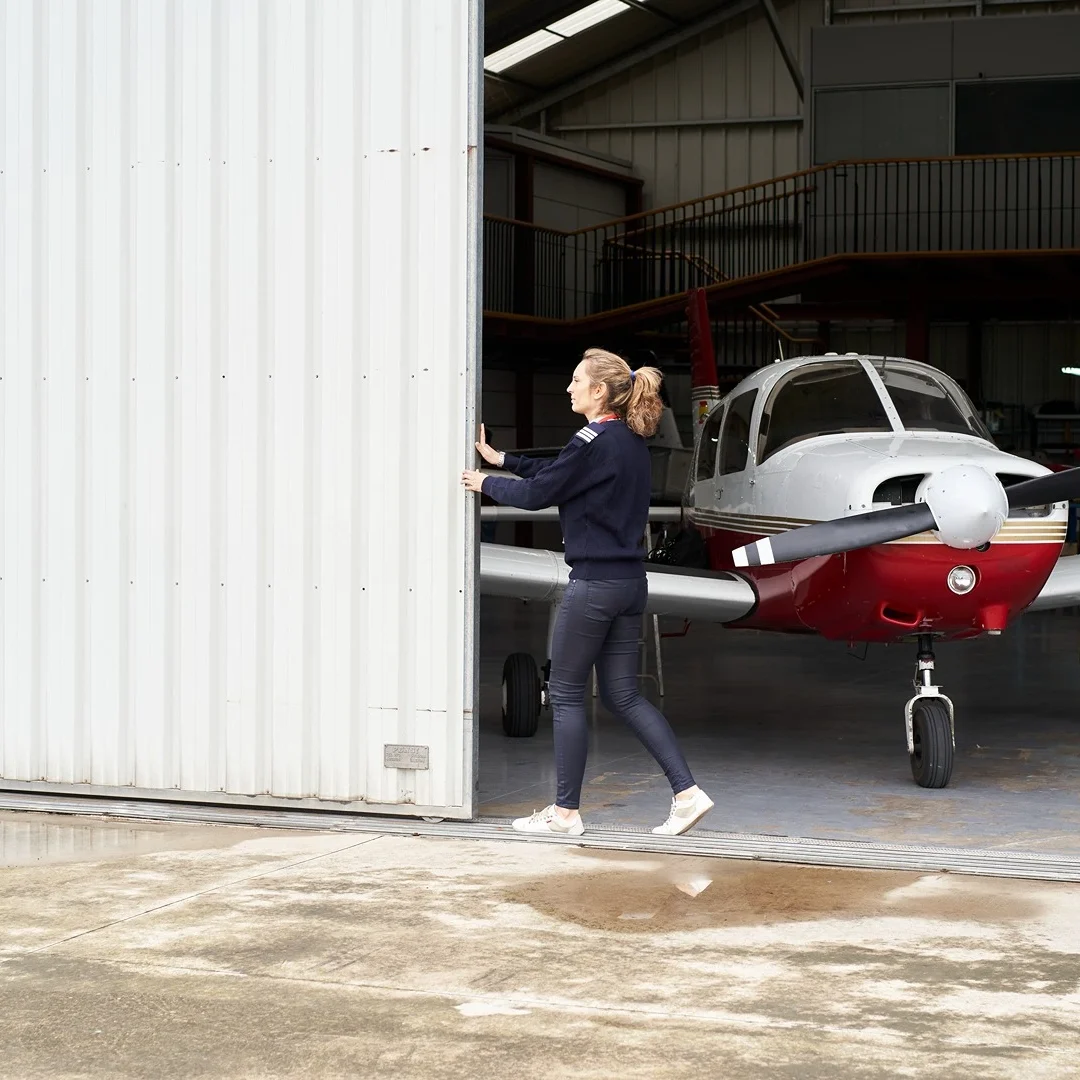 lady opening an aircraft hangar door